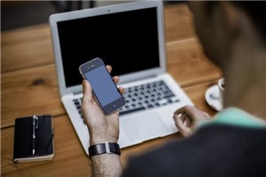 ラップトップと携帯を持ってテーブルに座っている男性